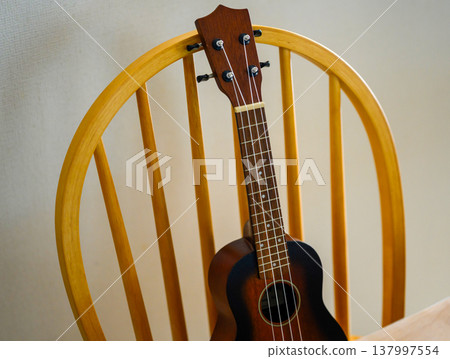 A ukulele leaning against a chair 137997554