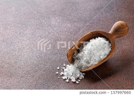 Sea salt crystals in wooden scoop on brown background Sea salt crystals in wooden scoop on brown background 137997660
