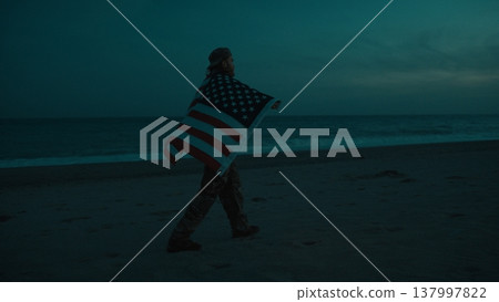 Soldier walks at night on beach near ocean during memorial celebration 137997822