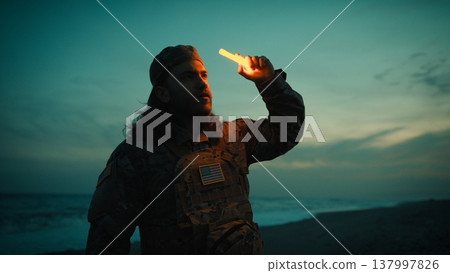 Lighting a chemical light by an American soldier at night on a beach near ocean 137997826