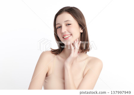A beautiful young woman with clean, fresh skin against a white background. Skincare, facial treatment, cosmetology, beauty, and spa. An elegant portrait of an woman. 137997949