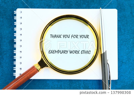 Heartfelt thank you for exemplary work ethic, magnified on a white spiral notebook with a pen, on a deep blue surface Heartfelt thank you for exemplary work ethic, magnified on a white spiral notebook with a pen, on a deep blue surface 137998308