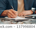 A businessman writes a business plan in a notebook. A man writes an idea with ballpoint pen. 137998804