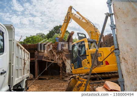 Demolition site of an old wooden house: Loading of waste wood by heavy machinery. 138000494