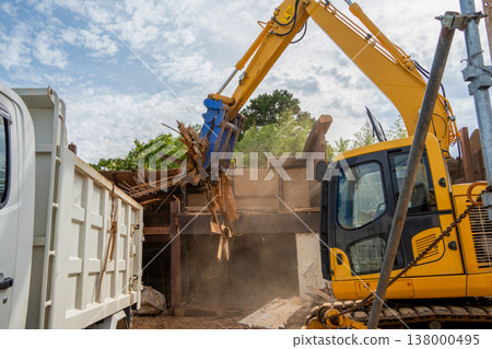 Demolition site of an old wooden house: Loading of waste wood by heavy machinery. 138000495
