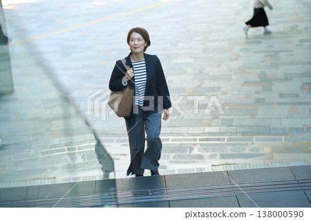 一位三十多歲的日本女商人,身穿海軍藍西裝外套,走在街上。 一位三十多歲的日本女商人,身穿海軍藍西裝外套,走在街上。 138000590
