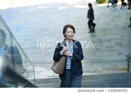 一位三十多歲的日本女商人,身穿海軍藍西裝外套,走在街上。 一位三十多歲的日本女商人,身穿海軍藍西裝外套,走在街上。 138000591