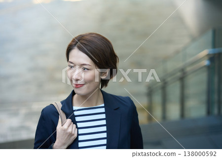 一位三十多歲的日本女商人,身穿海軍藍西裝外套,走在街上。 一位三十多歲的日本女商人,身穿海軍藍西裝外套,走在街上。 138000592