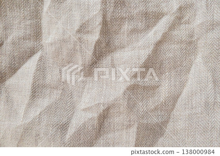 High quality horizontal shot of natural beige linen fabric with classic herringbone weave pattern. The surface features elegant organic wrinkles and soft shadows creating a sophisticated tactile feel High quality horizontal shot of natural beige linen fabric with classic herringbone weave pattern. The surface features elegant organic wrinkles and soft shadows creating a sophisticated tactile feel 138000984