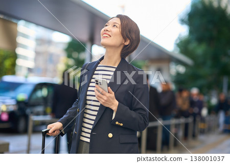 一位三十多歲的日本女商人拖著行李箱在城裡四處走動。 一位三十多歲的日本女商人拖著行李箱在城裡四處走動。 138001037