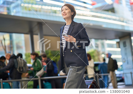 一位三十多歲的日本女商人拖著行李箱在城裡四處走動。 一位三十多歲的日本女商人拖著行李箱在城裡四處走動。 138001040