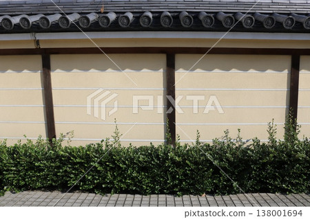 A background image featuring a simple streetscape with hedges and traditional Japanese-style walls. A background image featuring a simple streetscape with hedges and traditional Japanese-style walls. 138001694