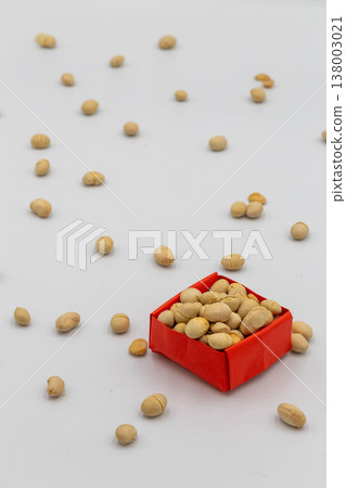 紅色摺紙盒裡裝著大豆,散落著一些大豆;白色背景上的節分撒豆圖案。 紅色摺紙盒裡裝著大豆,散落著一些大豆;白色背景上的節分撒豆圖案。 138003021