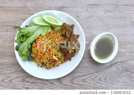 biryani rice cooked with braised beef meat stew in curry and fresh vegetable salad on plate dipping spicy chili sauce 138003032