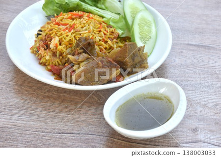 biryani rice cooked with braised beef meat stew in curry and fresh vegetable salad on plate dipping spicy chili sauce 138003033