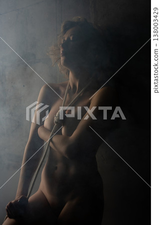 Shibari tied art with a naked woman in a misty setting capturing beauty and bondage Shibari tied art with a naked woman in a misty setting capturing beauty and bondage 138003429