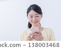 A young woman operating a smartphone 138003468