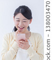 A young woman operating a smartphone 138003470