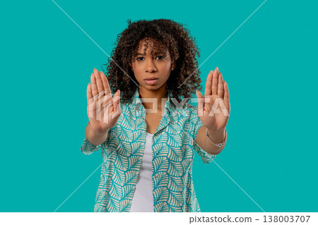 Serious african woman with open palm in stop gesture, assertive body language Serious african woman with open palm in stop gesture, assertive body language 138003707