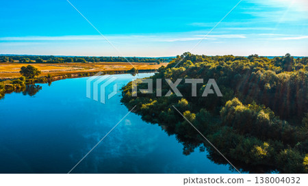 Aerial view of a beautiful summer landscape over river while dawn. Top view over river with a smooth water surface reflecting blue sky. Aerial view of a beautiful summer landscape over river while dawn. Top view over river with a smooth water surface reflecting blue sky. 138004032