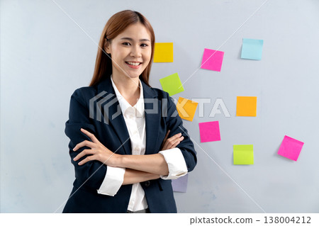 businesswoman standing in front of white board with multicolored sticky notes 138004212