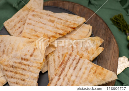 Pita bread with cheese baked on the grill. Thin, crispy triangular flatbreads with filling. Food on plate 138004727