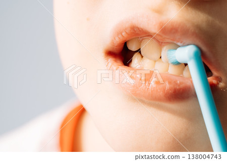 Child using single tuft toothbrush on teeth, close up oral hygiene routine 138004743