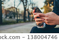 Close up Male hands with smartphone, outdoors. Businessman is typing text messages on mobile phone sitting in the park. Human holds cell phone close up. Man holds mobile phone. Connection concept. 138004746