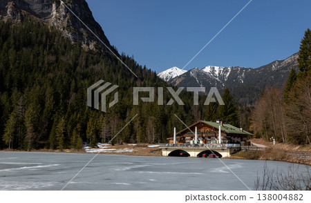 Frozen alpine lake with mountain lodge in late winter, Bavaria, Germany 138004882