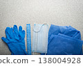 Healthcare background of disposable face mask, gloves, hat and scrubs laying on table flat lay view 138004928