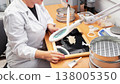 A specialist from a biological laboratory of an agricultural enterprise uses an optical device to analyze the quality of grain and determine the degree of pest infestation 138005350