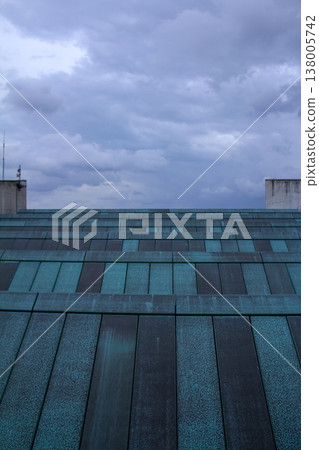 Close-up view of the rooftop of building with the blue sky and clouds. Building exterior. Close-up view of the rooftop of building with the blue sky and clouds. Building exterior. 138005742