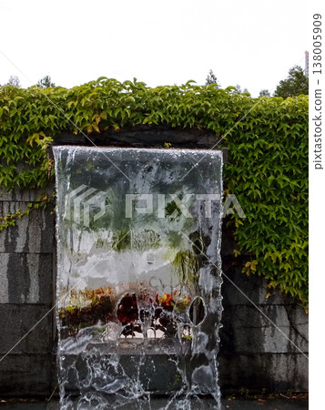 Close-up view of a cascading feature water fountain in a public park. Powerful spout of cascading water pours into the pool. Close-up view of a cascading feature water fountain in a public park. Powerful spout of cascading water pours into the pool. 138005909