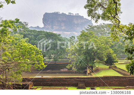 Sigiriya ancient rock fortress with gardens in Sri Lanka. Ancient Fortress Rock Structure Amidst Lush Green Landscape with Historical Garden Remains and Water Features Sigiriya ancient rock fortress with gardens in Sri Lanka. Ancient Fortress Rock Structure Amidst Lush Green Landscape with Historical Garden Remains and Water Features 138006188