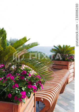 Cozy Outdoor Bench Surrounded By Nature. Serene Seating Area With Colorful Flowers By Gentle Sea 138006280