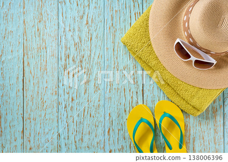 beach accessories: straw hat, bag, sunglasses and colorful beach flip flops on a blue wooden background, top view . beach accessories: straw hat, bag, sunglasses and colorful beach flip flops on a blue wooden background, top view . 138006396