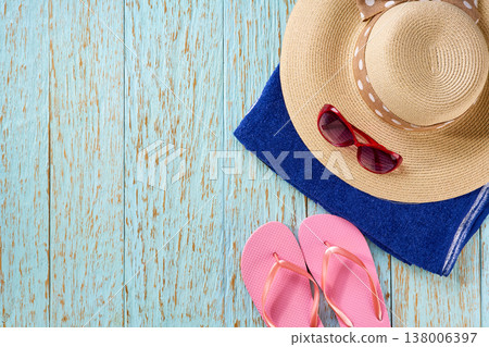 beach accessories: straw hat, bag, sunglasses and colorful beach flip flops on a blue wooden background, top view . beach accessories: straw hat, bag, sunglasses and colorful beach flip flops on a blue wooden background, top view . 138006397