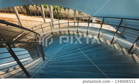 Modern curved staircase with metal railing and ambient lighting in evening interior, Contemporary illuminated concrete stairs with smooth lines and glow 4k 138006551