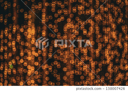 Abstract bokeh effect of the gold, yellow lights on black background. City street light decorations. Rows of LED gold colored light spots with black background. Abstract bokeh effect of the gold, yellow lights on black background. City street light decorations. Rows of LED gold colored light spots with black background. 138007426
