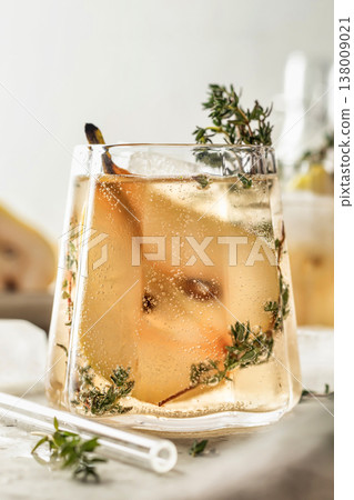 Glass of pear thyme spritzer cocktail on textured background close up. Festive homemade drink recipe for party 138009021