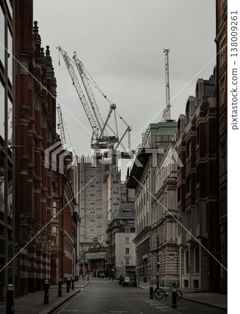 In the soft, overcast light typical of a London afternoon, this quiet thoroughfare serves as a stage for a metropolis in flux. The perspective humbles the viewer, placing them within the shadowed 138009261