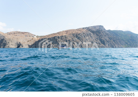 A boat is in the water near a rocky shore. A boat is in the water near a rocky shore. 138009605