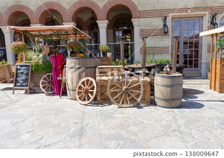 Several wooden wheels and barrels stand in front of the building. Several wooden wheels and barrels stand in front of the building. 138009647