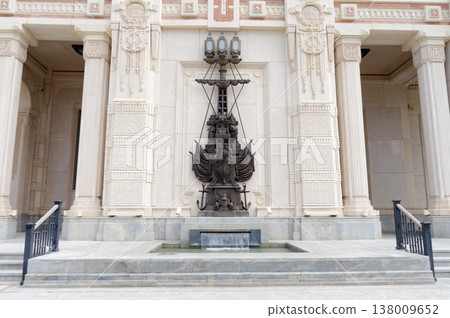 A statue of a ship is on the side of a building. 138009652