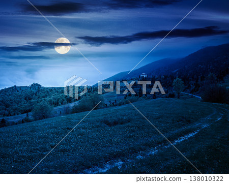 remote countryside in mountain landscape at night. hazy weather during spring in full moon light. dirt road through lush green pasture on a hill. mysterious alpine vista with deciduous trees remote countryside in mountain landscape at night. hazy weather during spring in full moon light. dirt road through lush green pasture on a hill. mysterious alpine vista with deciduous trees 138010322