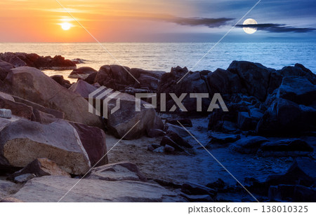 sea with rocky shore. day meet night. sun and moon over beautiful autumn equinox scenery and vacation concept on the rocky beach at twilight. scenic destination of seaside near old resort town 138010325