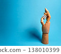 Wooden hand holding dice against blue background during creative art session 138010399