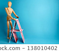 Wooden figure builds a house of cards on a blue background during daytime in a simple setting 138010402