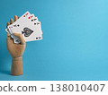 Playing cards held by a wooden hand against a blue background with focus on four aces and a heart symbol 138010407