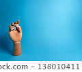 Wooden hand holds two dice against a bright blue background in a playful display of chance and games 138010411